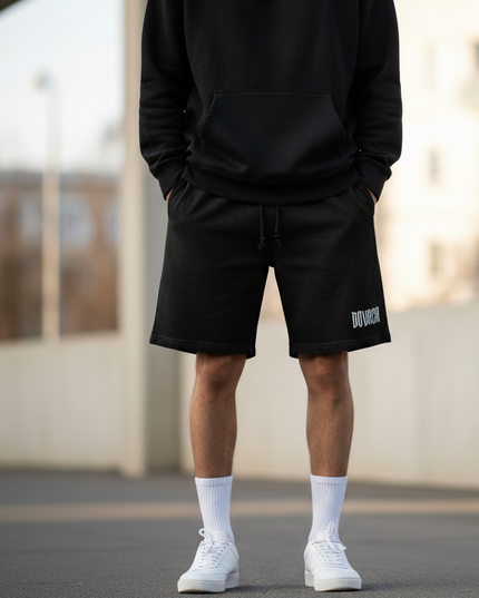 Person wearing a black tracksuit with a brand logo, standing outdoors.