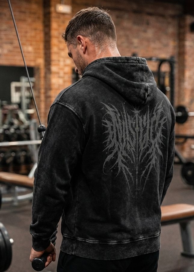 Man wearing a black hoodie with a tribal design in a gym setting