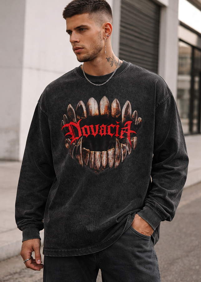 Man wearing a black sweatshirt with a graphic design and text outdoors.