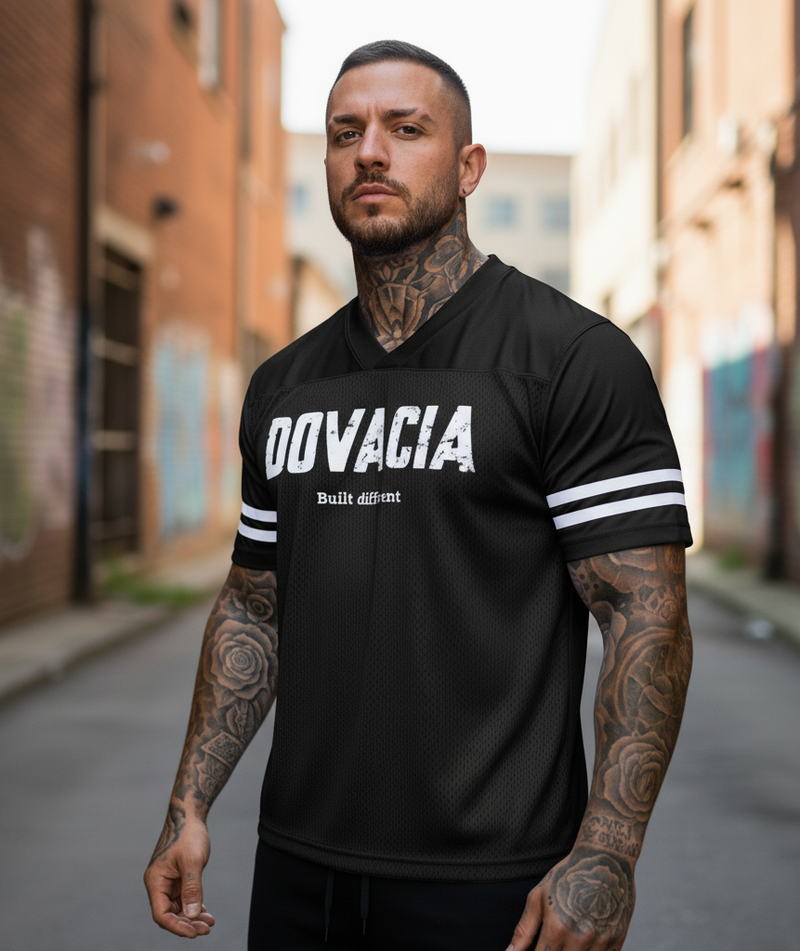 Man wearing a black 'DOVACIA' t-shirt with white text in an urban setting