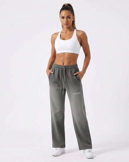 Woman wearing gray sweatpants with a brand logo on a white background